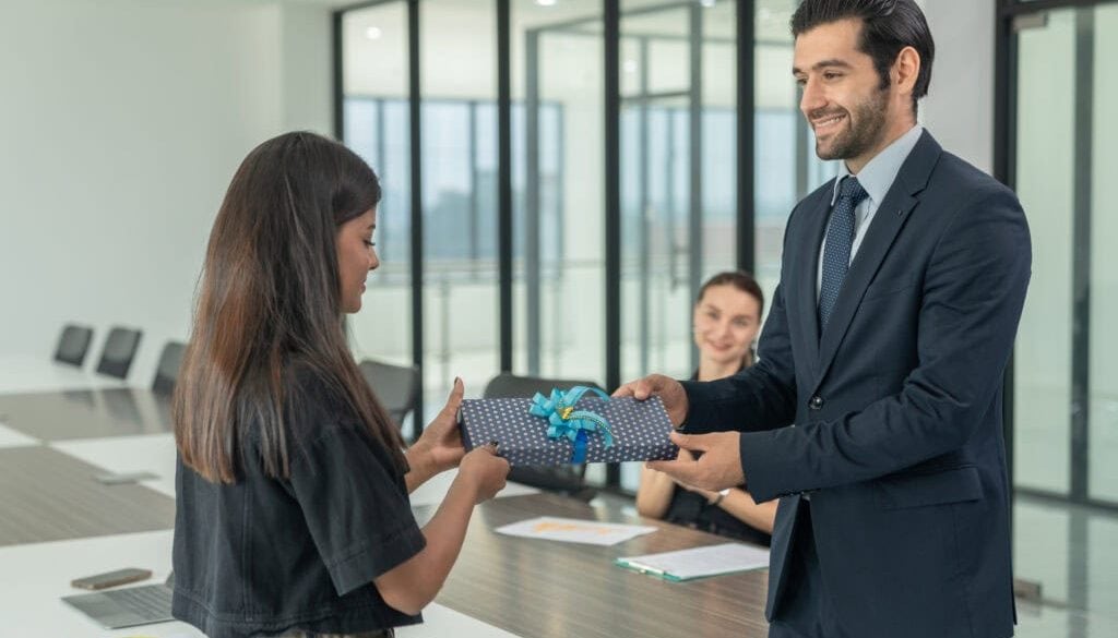Businessman giving a gift box to his female colleague during a meeting