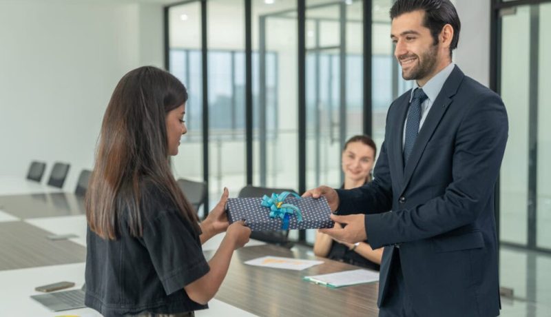 Businessman giving a gift box to his female colleague during a meeting
