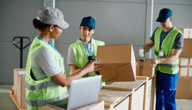 Group of warehouse workers cooperating in preparation of distribution packages