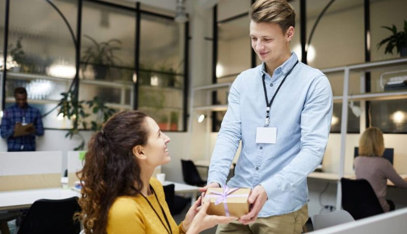 Happy lady accepting gift from colleague