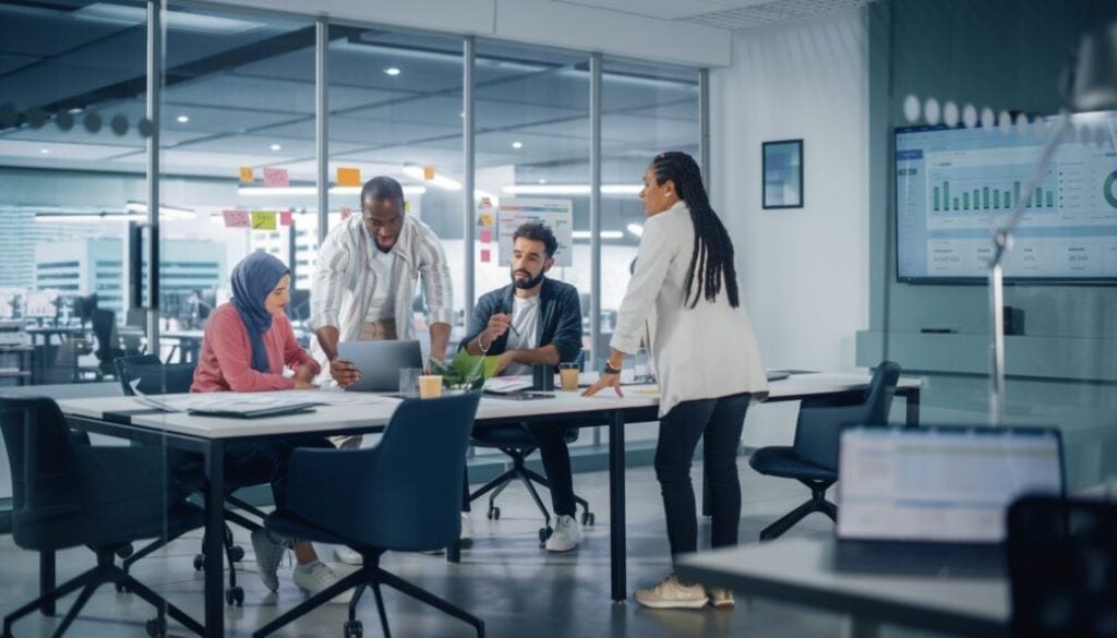 Multi-Ethnic Office Conference Room Meeting Multicultural Team of Four Creative Entrepreneurs Talk Discuss Growth Strategy Diverse Young Businesspeople work on Digital e-Commerce Startup