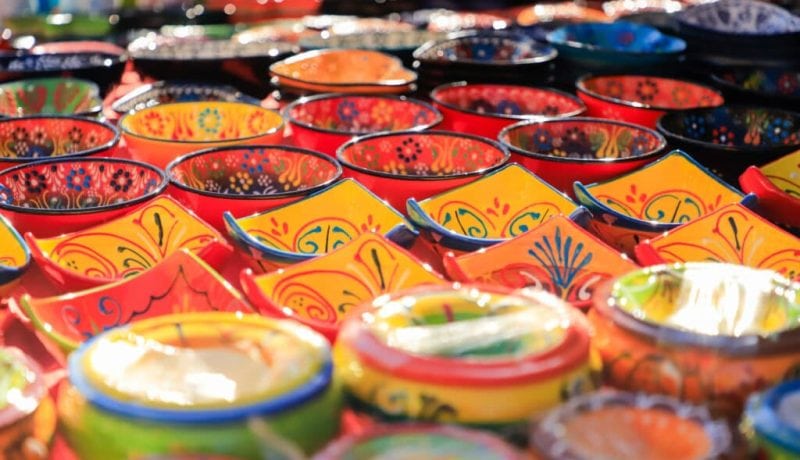 Colorful Mexican ceramic bowls and dishes displayed in a market setting.