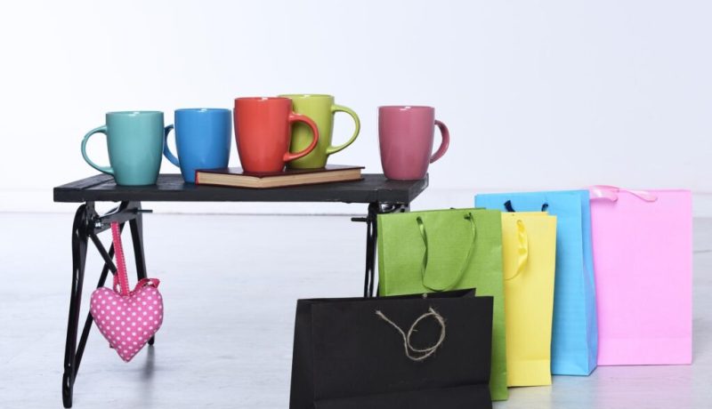 Assorted colorful mugs and gift bags for promotional products and branding.