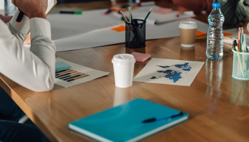 Business meeting with documents, coffee, and water bottles on a wooden table.