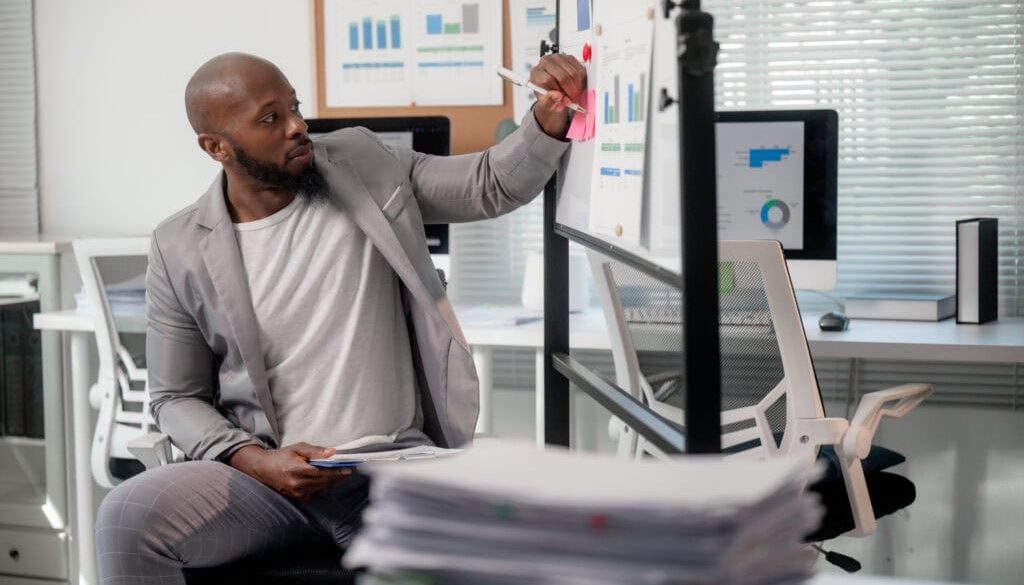 Businessman writing on whiteboard analyzing data and preparing a presentation in the office
