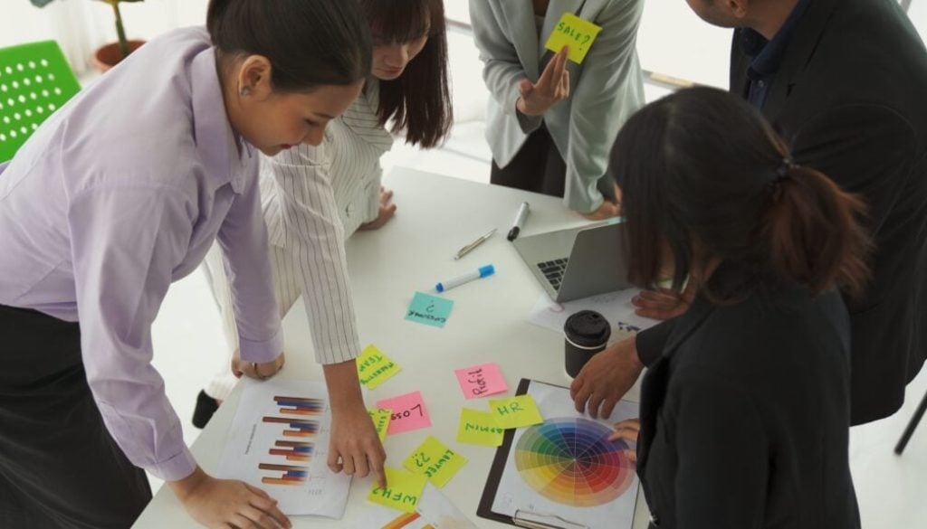 Business team collaborating on colorful marketing materials in a modern office.
