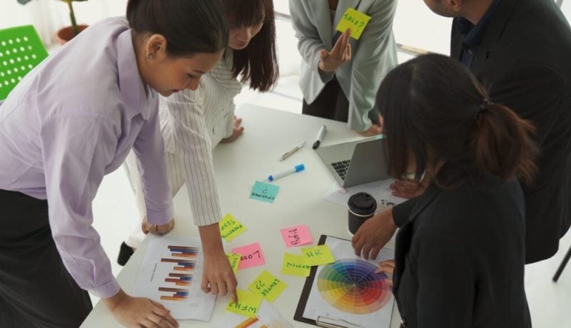 Business team collaborating on colorful marketing materials in a modern office.