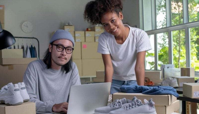 Two people working on custom shoe packaging and branding at a workspace.