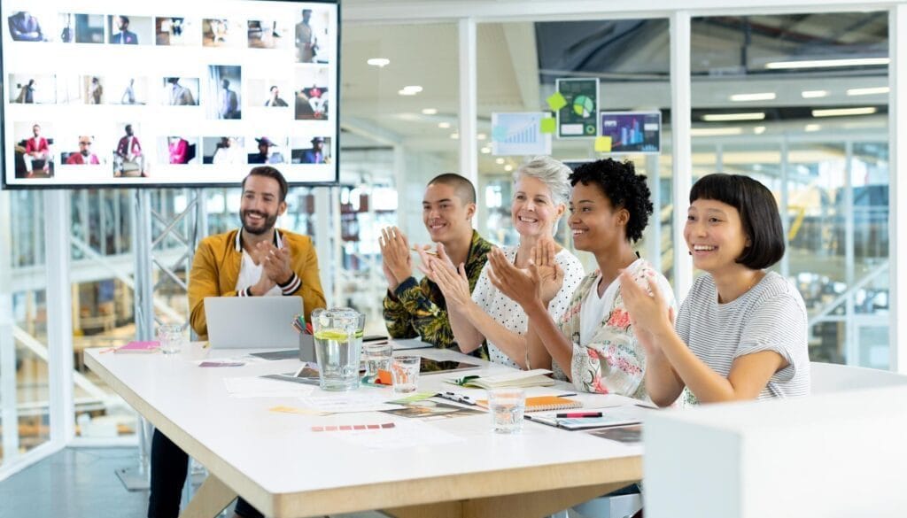 Happy diverse team celebrating success during a business meeting in a modern office.