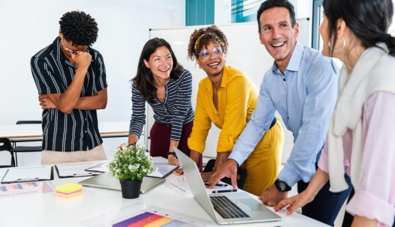 Diverse team collaborating and smiling in a modern office meeting room.