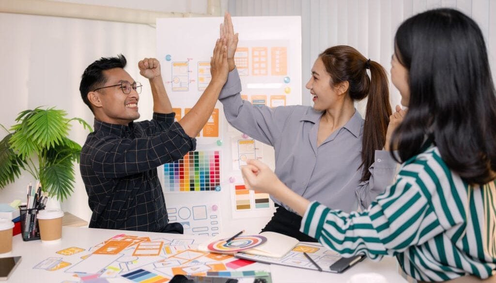 Team celebrating success with high-fives in a creative office environment.