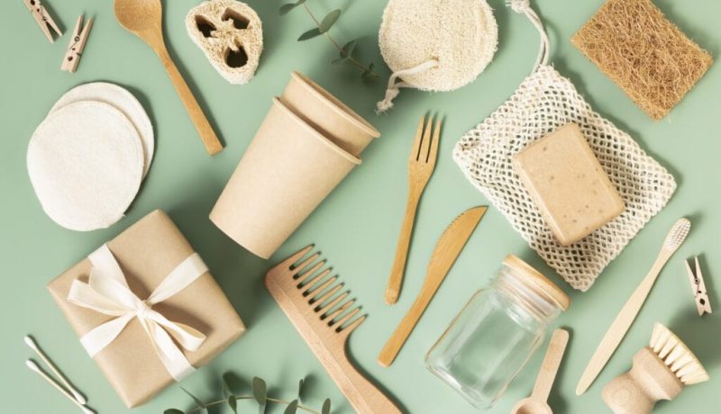 Set of eco-friendly tableware and cleaning products on pastel green background flat lay stop plastic pollution