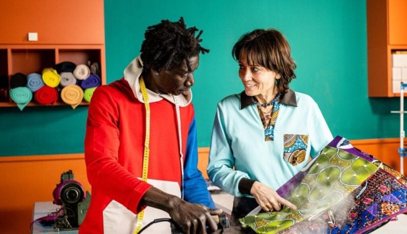 Two women discussing custom promotional products in a colorful workspace.