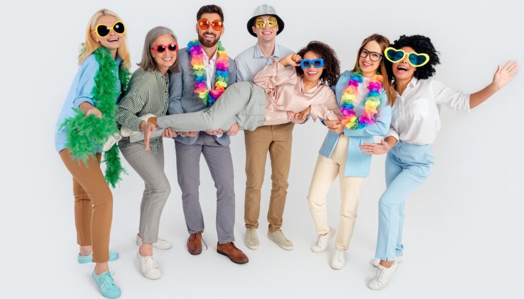 Group of diverse colleagues posing cheerfully in colorful outfits against a neutral background showcasing teamwork and fun atmosphere