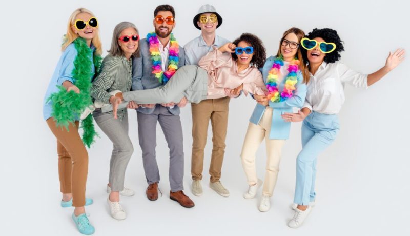 Group of diverse people wearing colorful party accessories and sunglasses, celebrating together.