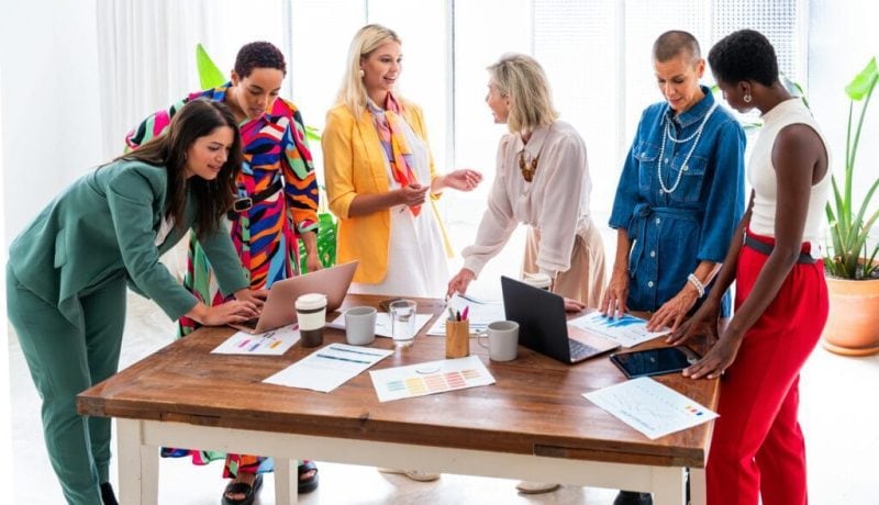 Diverse team collaborating around a wooden table in a bright office space.