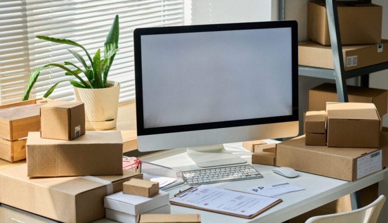 Desktop computer with blank screen standing among packed boxes