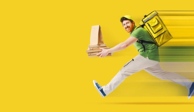 Happy delivery person with packages and backpack on yellow background.