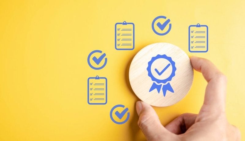 Hand holding a stamp with a checkmark, surrounded by checklist icons on yellow background.