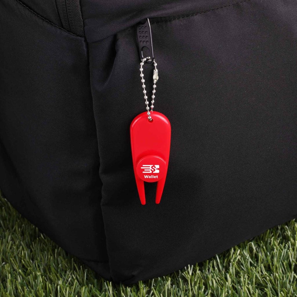 Red plastic wallet locator keychain attached to a black backpack, with the word 'Wallet' printed on a round button and a small chain leash visible.