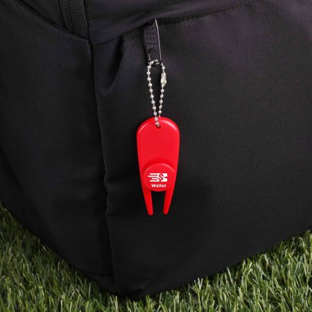 Red plastic wallet locator keychain attached to a black backpack, with the word 'Wallet' printed on a round button and a small chain leash visible.