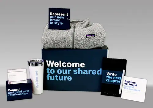 Branding kit on a gray gradient background: a navy box with white text 'Welcome to our shared future', a gray hoodie, booklet cards with brand messages like 'Represent our new brand in style' and 'Write the next chapter', plus a mug and business cards.